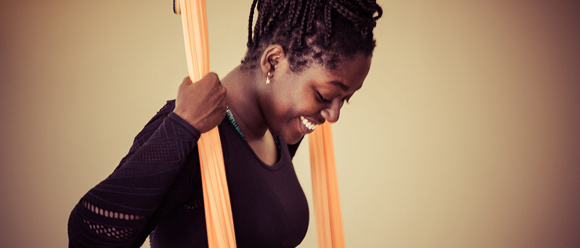 Farbige steht im Aerial Yoga Tuch